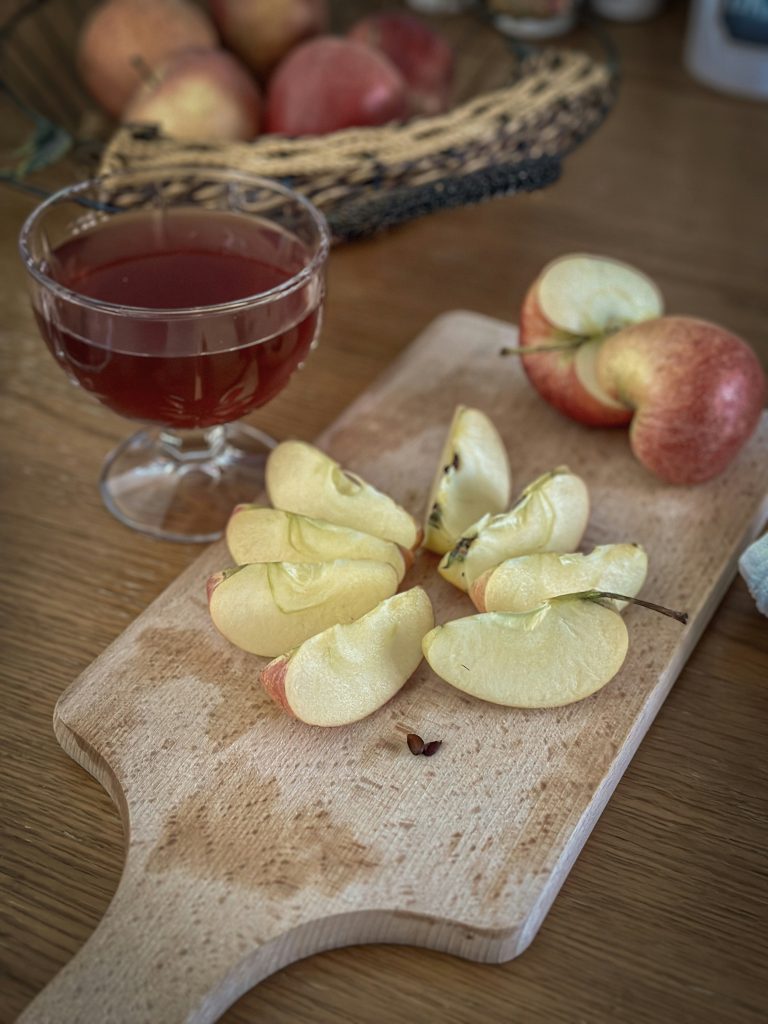Glass of cider with sliced apples on a wooden board